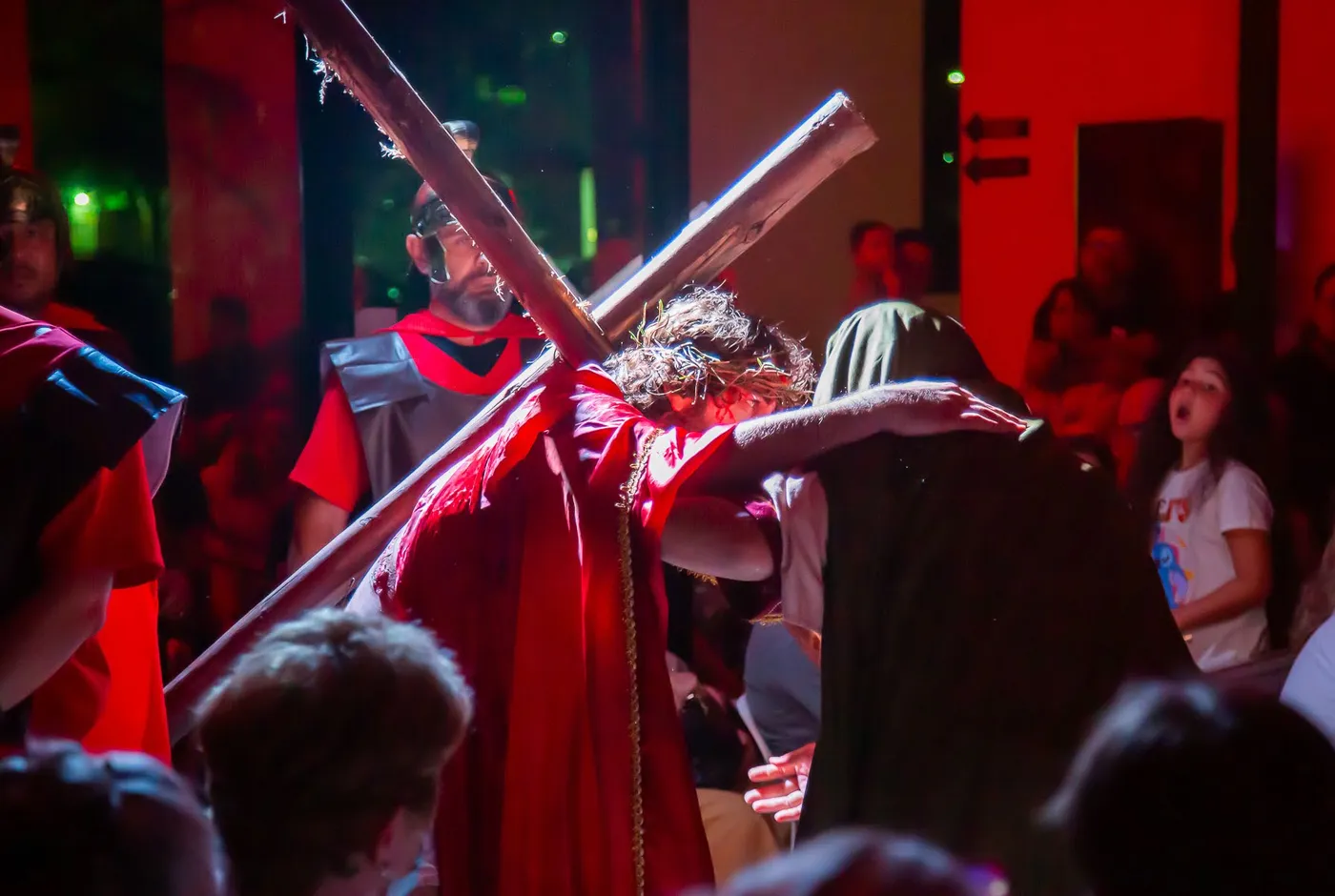 Christ under the cross, embraced, in warm red and gold light