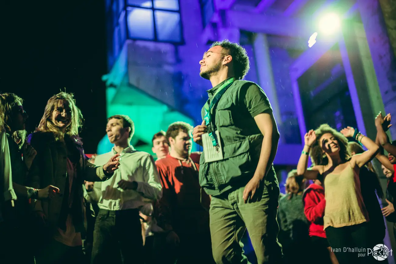 Yuri, the show's founder and director, standing amid the dancing crowd under green light and falling confetti